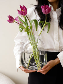 Clear glass vase shaped like a perfume bottle for decorative flower display