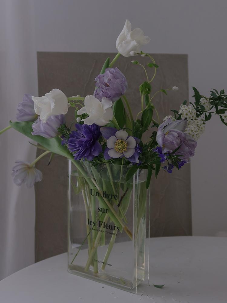 Clear acrylic flower vase shaped like an open book