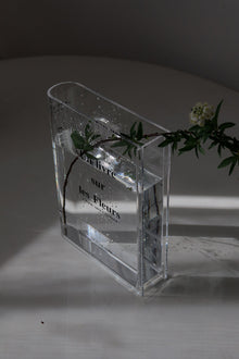 Clear acrylic flower vase shaped like an open book