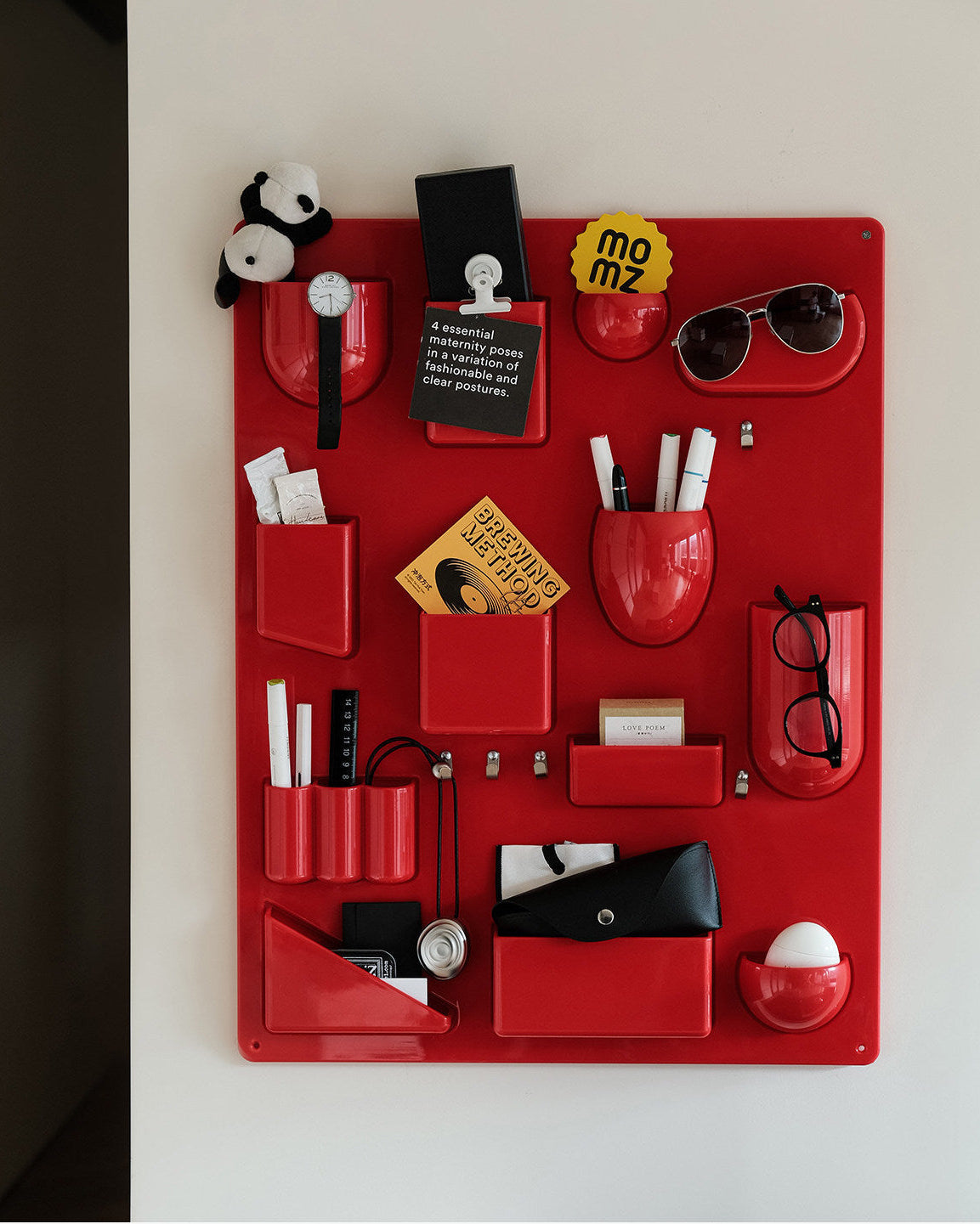 Red wall-mounted pocket organizer panel with compartments and hooks