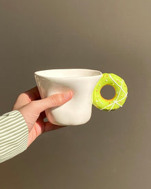 Ceramic mug with a playful donut-shaped handle