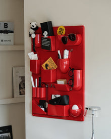 Red wall-mounted pocket organizer panel with compartments and hooks