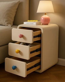 Narrow bedside cabinet with playful drawer knobs and compact storage