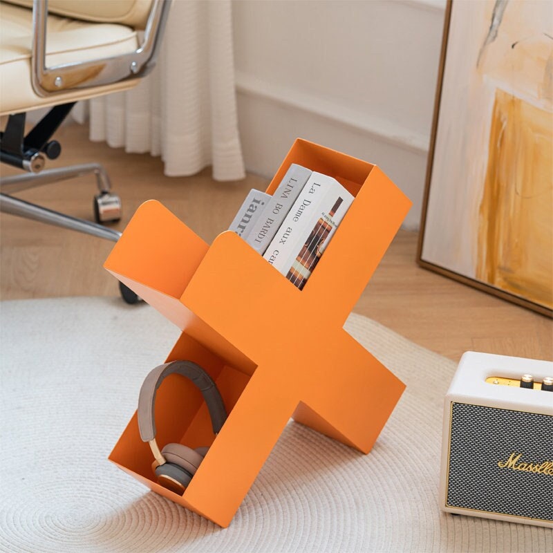 Orange X-shaped metal bookshelf for books, magazines, and home decor