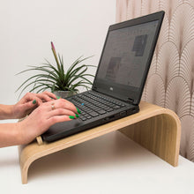 Oak wooden laptop stand with ventilation cutouts for a desk workspace